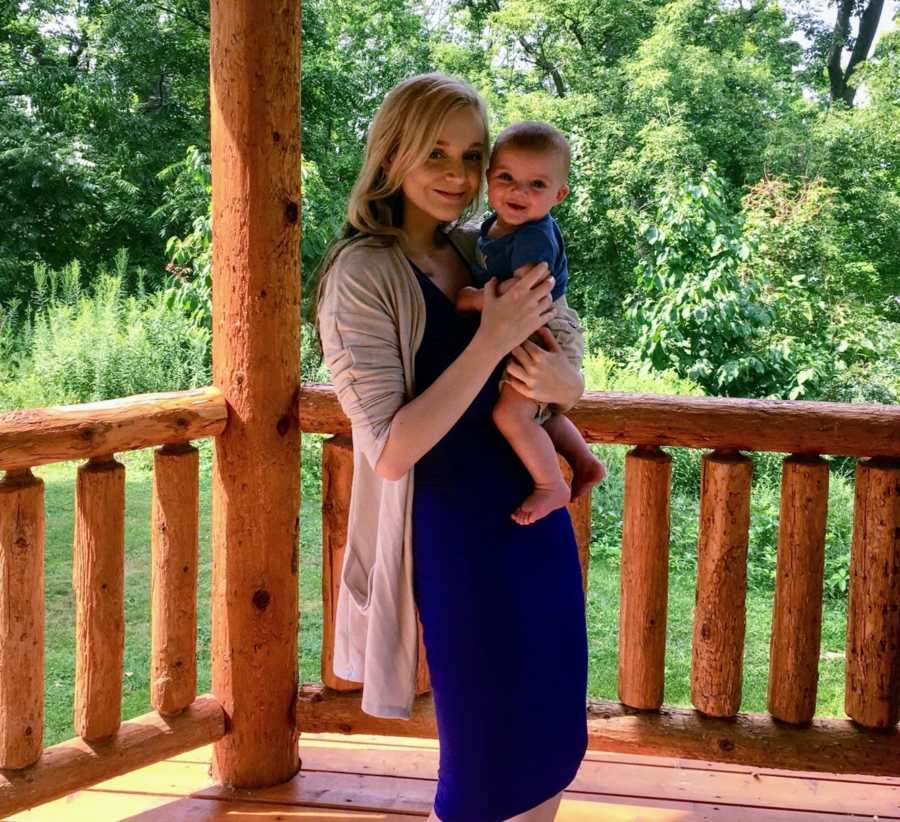 Mother holds son with Hirschsprung Disease while standing on log porch