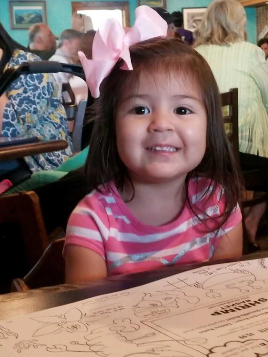 Little girl with acute flaccid myelitis smiling at restaurant table