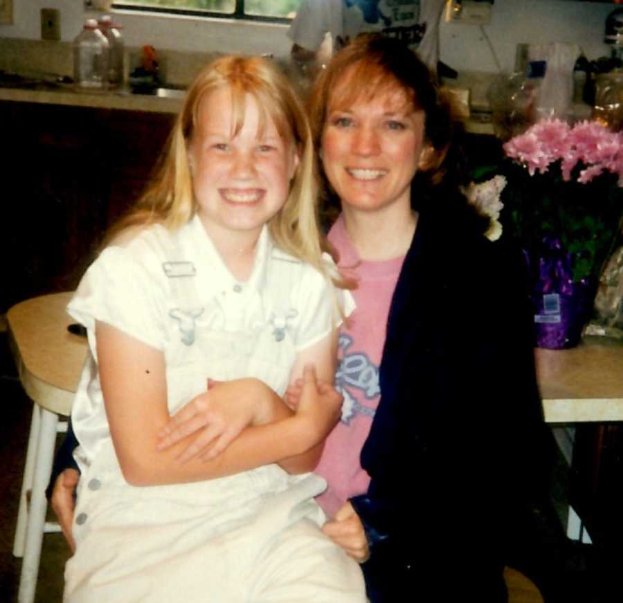 Teen who is bullied at school sits in kitchen beside her mother