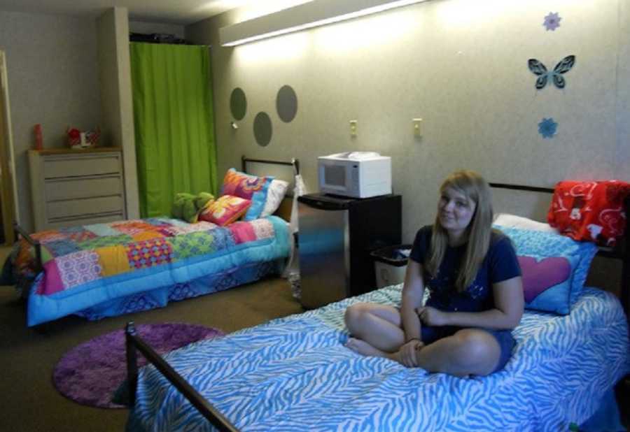 Teen girl with endometriosis sits on bed in dorm room
