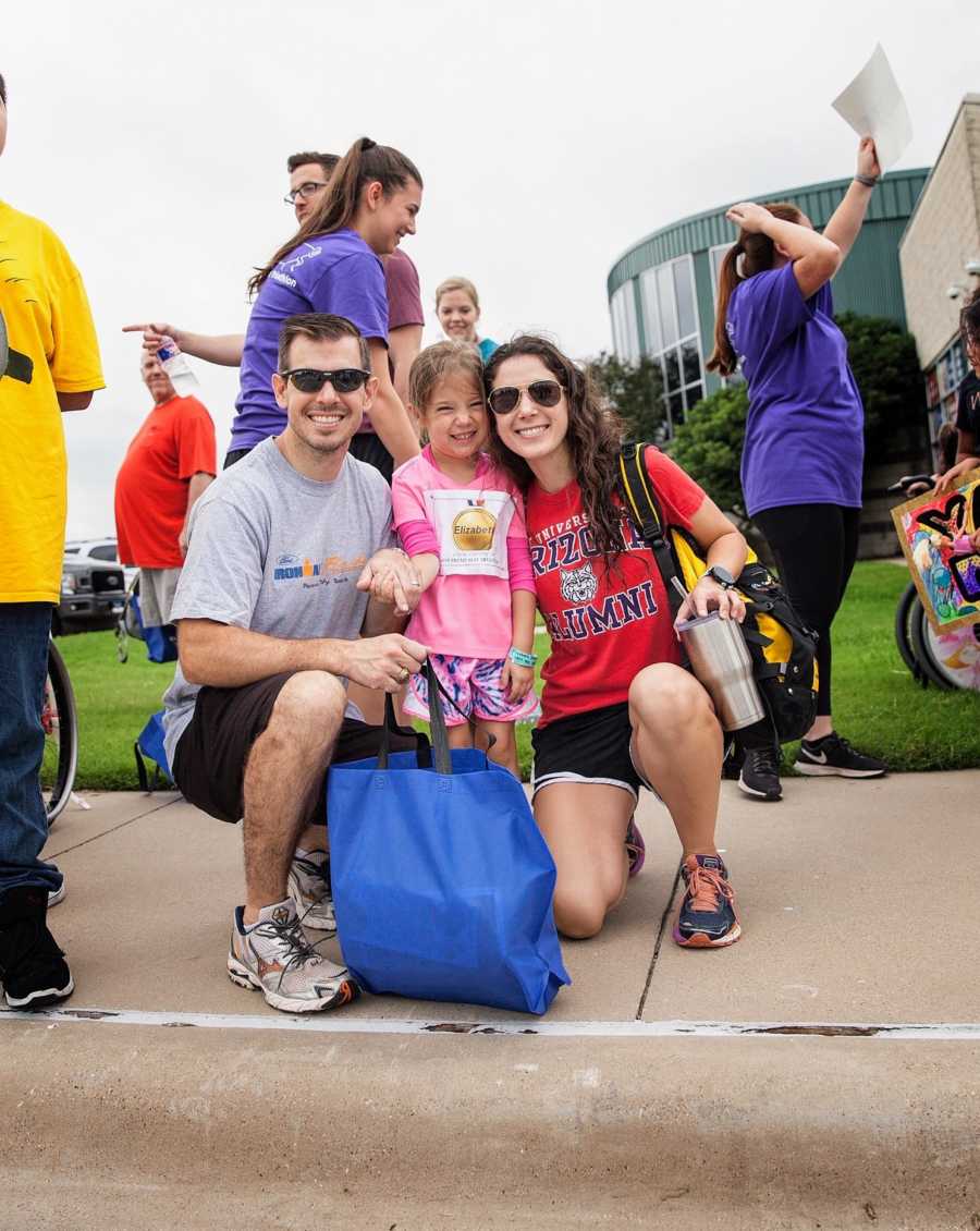 Parents crouch down next to daughter who competed in Cook Children's ‘Tri My Best’ Triathlon