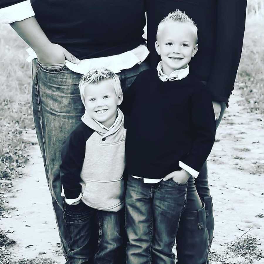 Young boys stand smiling in front of their parents