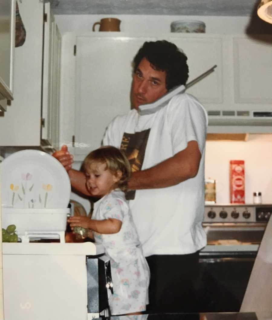 Man stands in kitchen on phone white daughter stands beside him