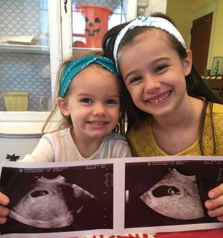 Young sisters hold up ultrasound pictures of their new sibling