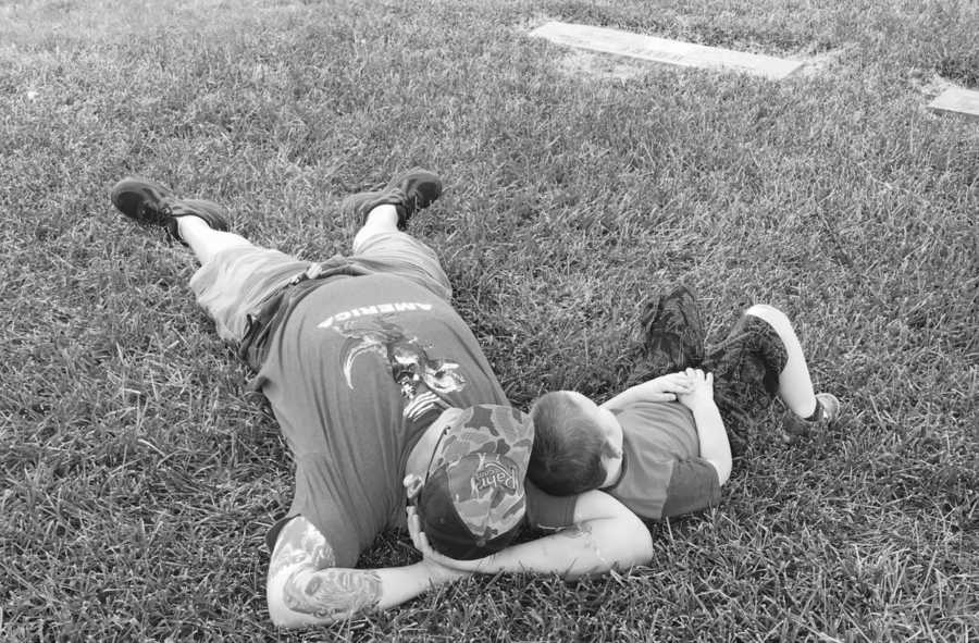 Father laying in grass with son resting on his arm who have had two baby daughter pass away