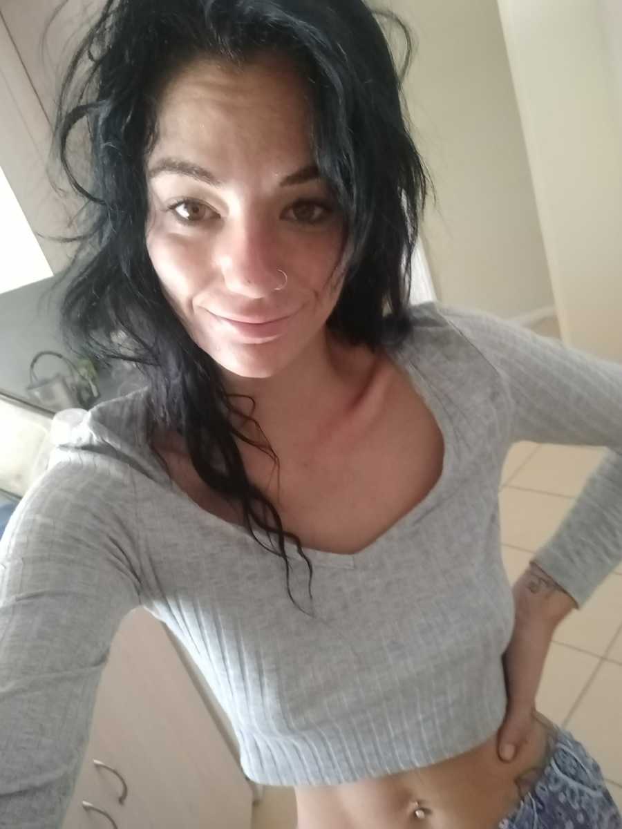 Woman with depression smiles in selfie with hand on her hip