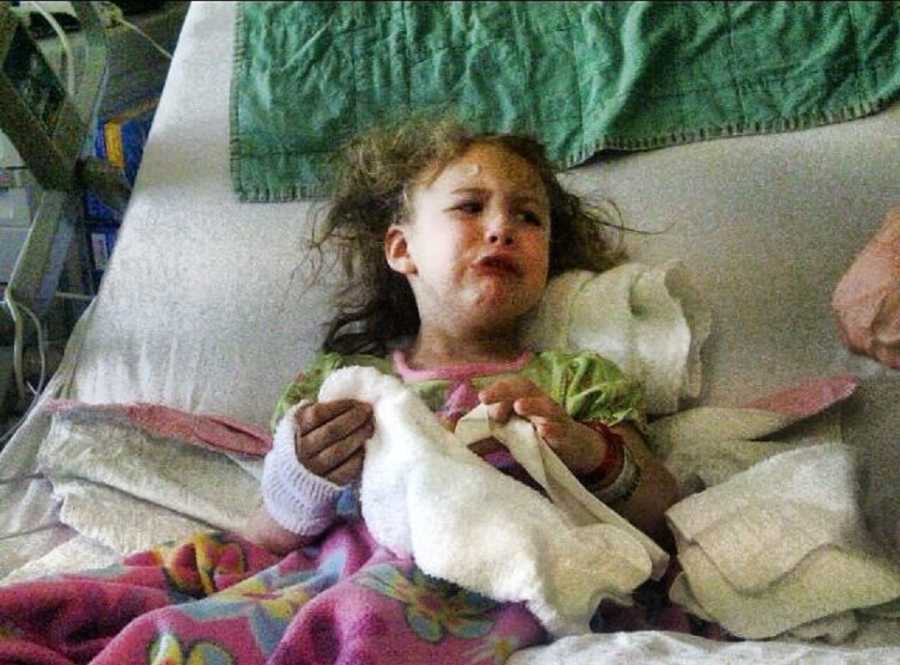 Little girl with absence and petit mal seizures cries in hospital bed while holding onto towel