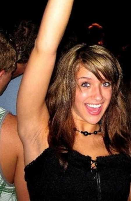 Young woman who abuses drugs and alcohol smiling while raising arm in the air 