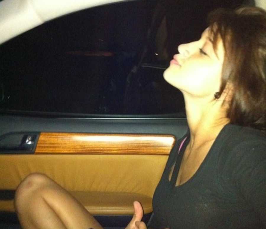 Young woman who abuses drugs and alcohol sits in car with eyes closed and chin pointed up