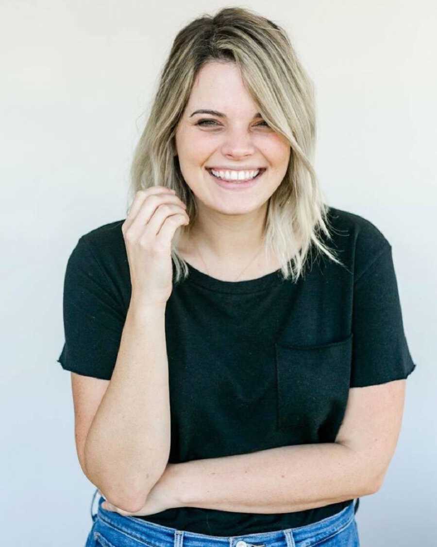 woman smiles while resting elbow on her crossed arm