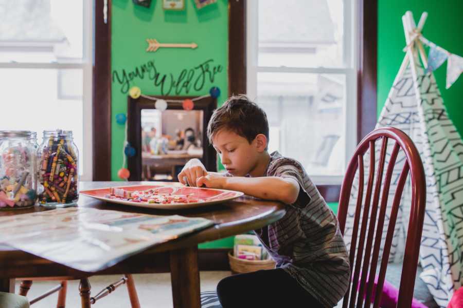 Little boy in foster care sits at table in home crafting
