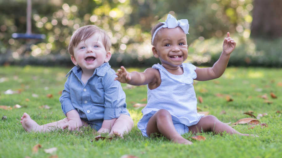Little boy smiles as he sits outside with adopted sister