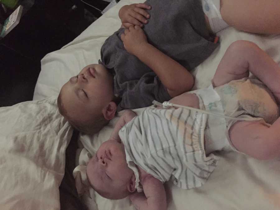 Newborn home from NICU lying asleep with older brother
