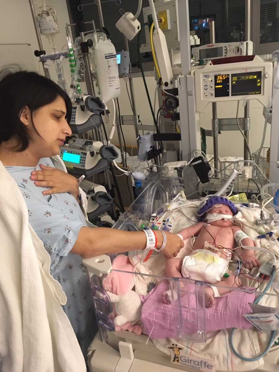 Woman who suffered painful child birth stands beside newborn in NICU holding her hand