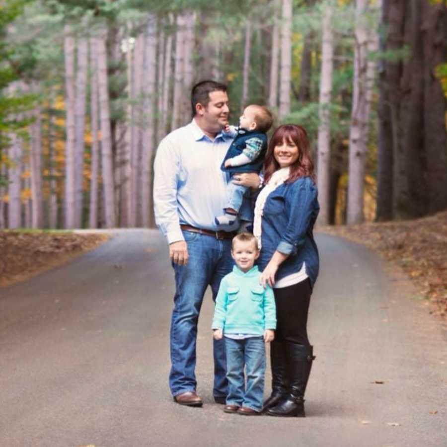 Husband and wife stand in street with their oldest son while husband holds toddler with Febrile Seizures for photoshoot
