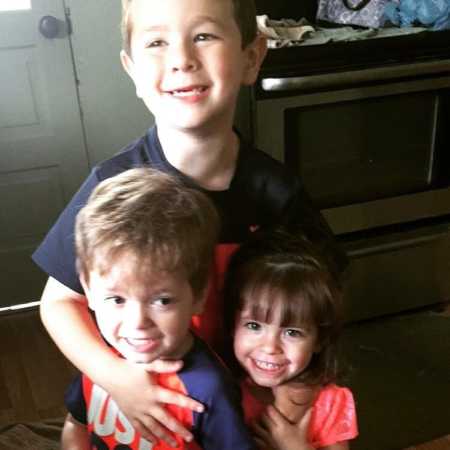 Young boy stands hugging his mothers' two young foster children