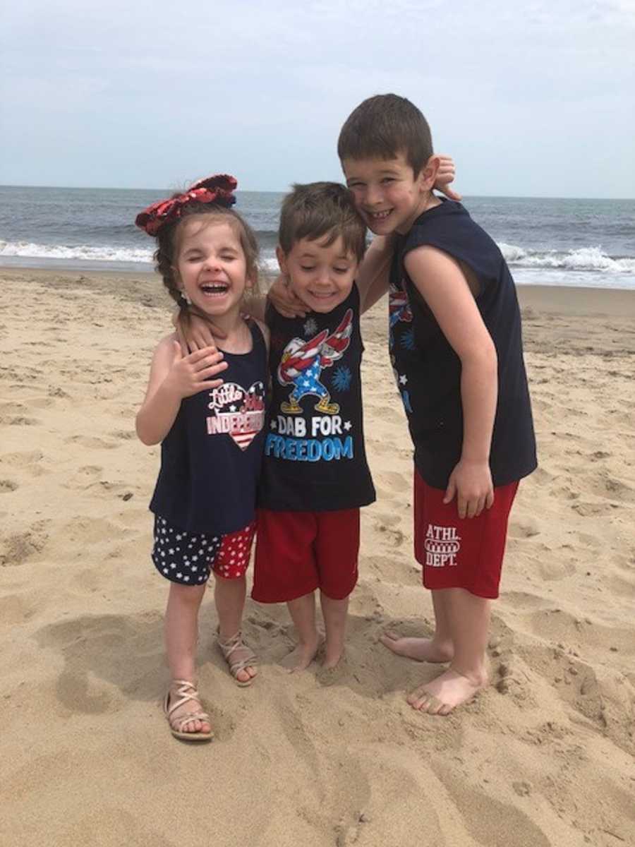 Young boy stands on beach with his mothers' two foster children