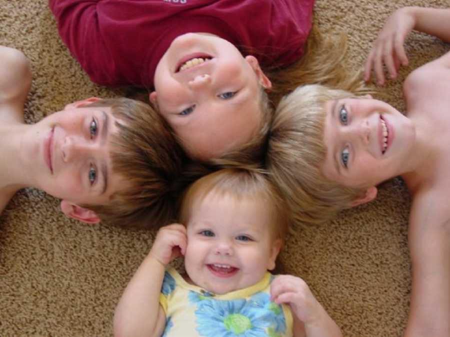 Aerial of four children laying on floor with their heads touching