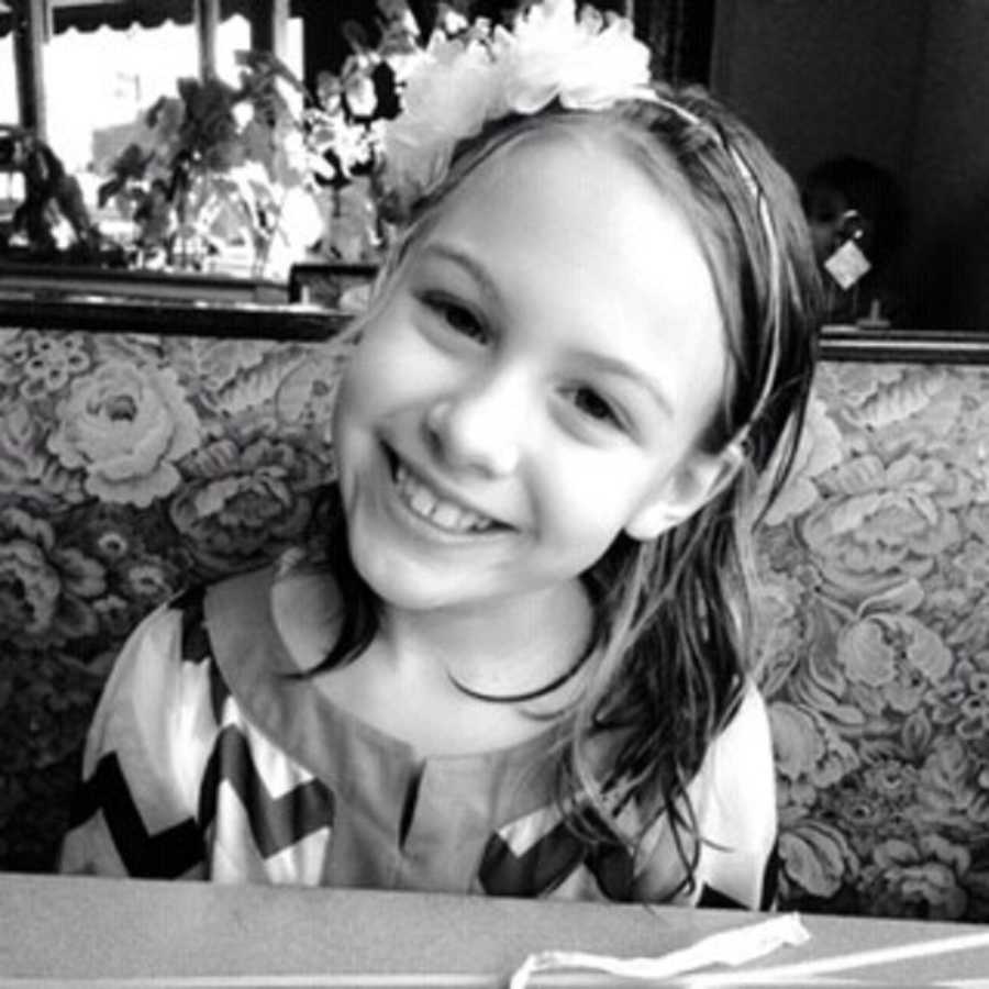Young girl with absence and petit mal seizures smiles in booth at restaurant