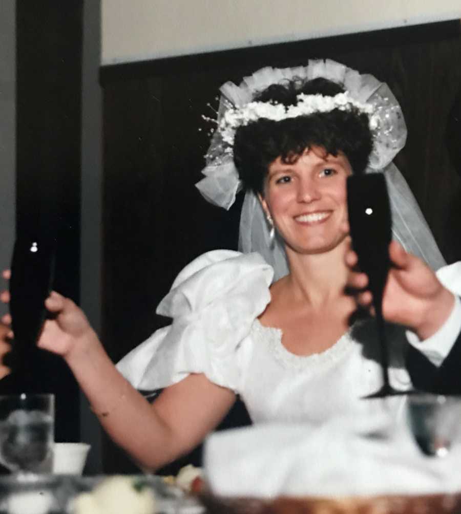Bride smiles as she raises her glass at wedding reception