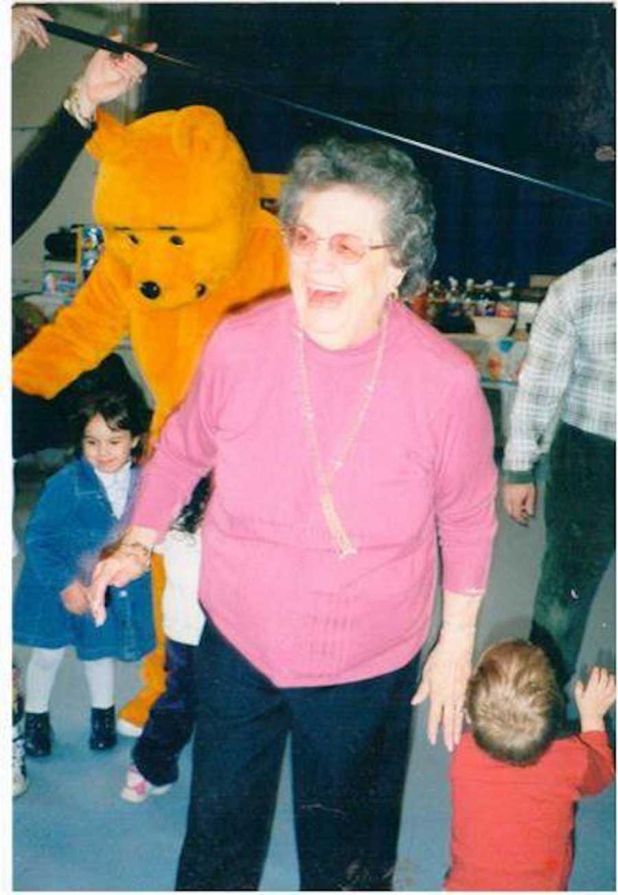 Woman who has since passed away stands smiling beside young children and person in Winnie the Pooh costume