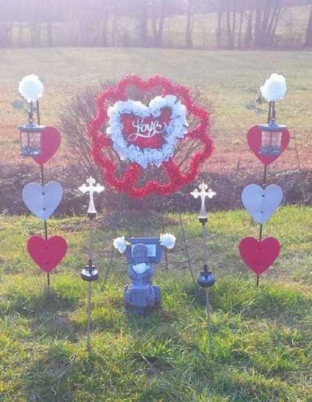 Small angel statue sits outside with Valentine's Day decoration around it