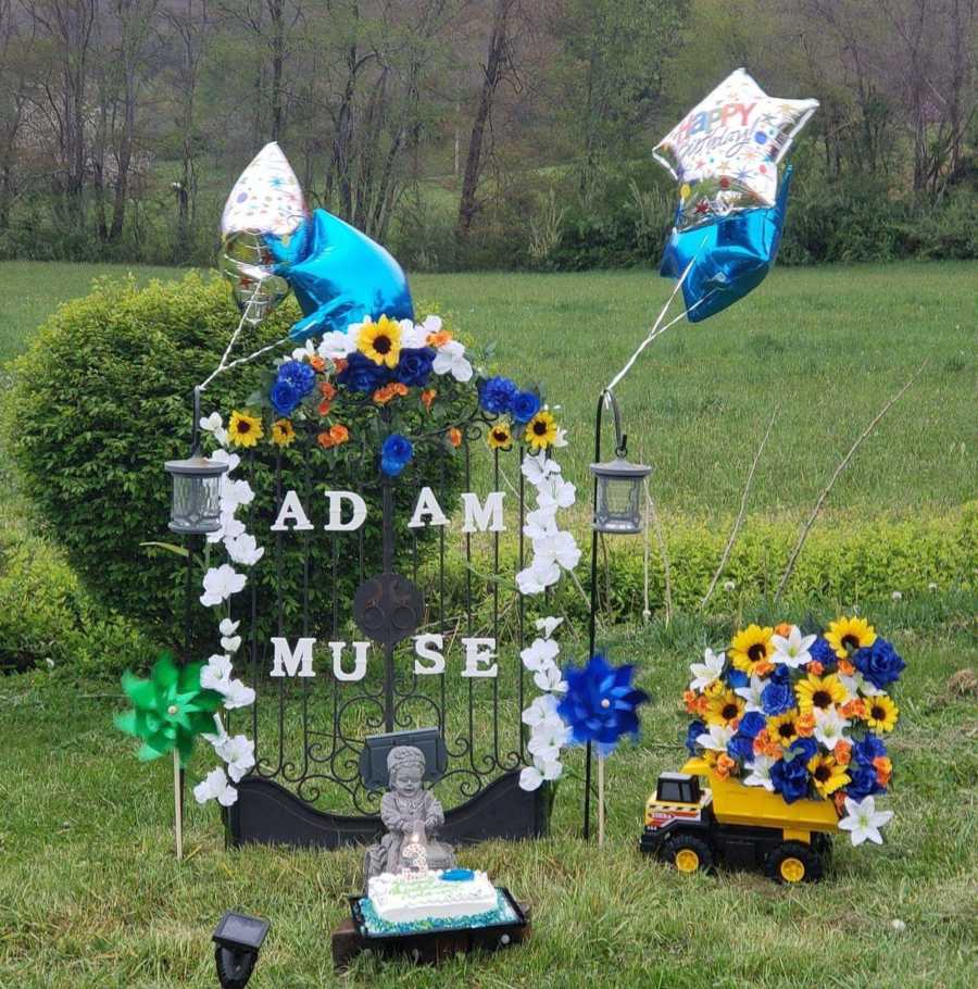 Statue outside that is covered in flowers and balloons for baby boy that was miscarried