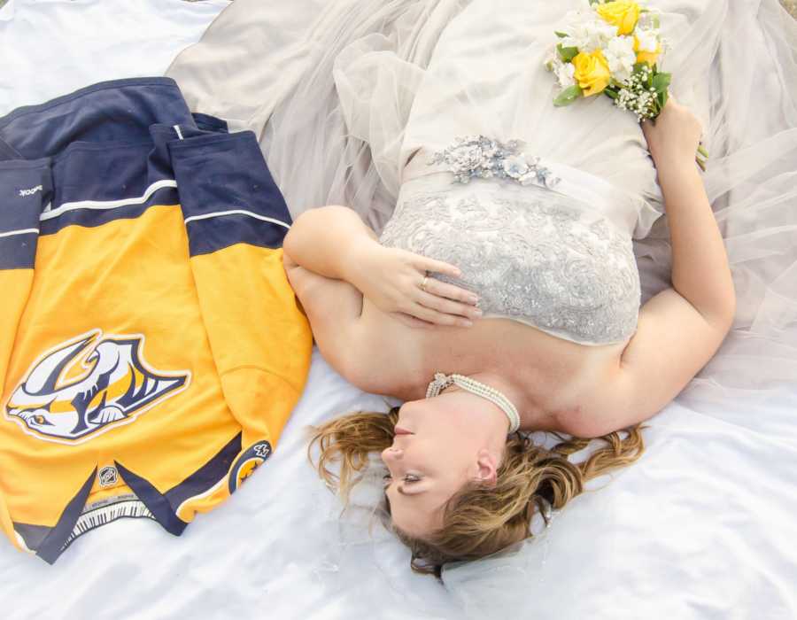 Woman lays down in wedding dress looking at Nashville Predators jersey laying next to her for deceased husband