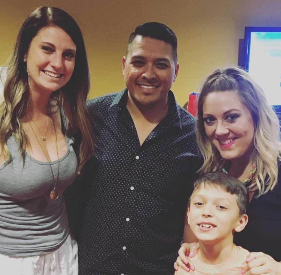 Young boy stands smiling with mom, dad, and dad's new wife