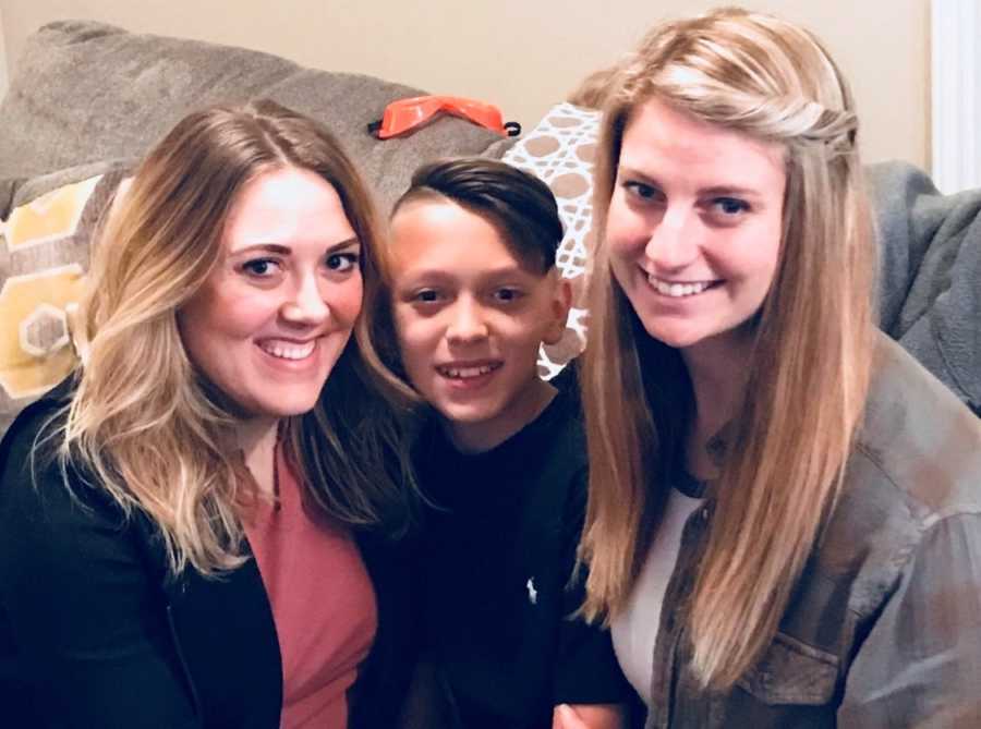 Young boy sits on couch with mom and stepmom