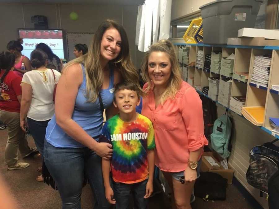 Young boy stands smiling with mom and step mom