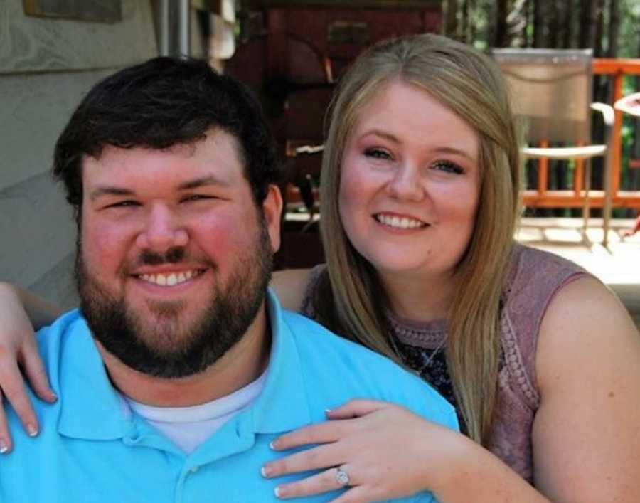 Wife with endometriosis sits beside husband with hands on his shoulders