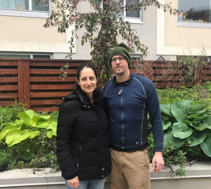 Husband and wife stand arm in arm outside smiling after birth of stillborn 