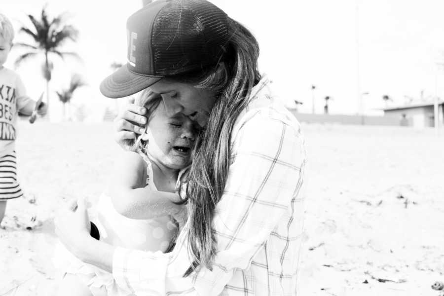 Mother holds one of her triplets who is crying close to her chest