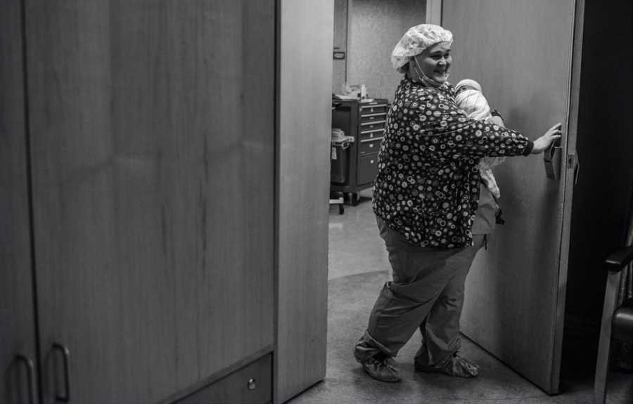 Nurse opening door with newborn in her arms