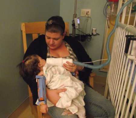 Mother sits in rocking chair holding baby in PICU