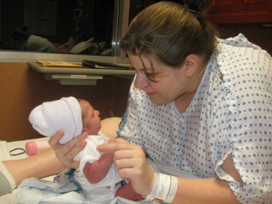 Mother leans over in hospital bed looking at newborn with cleft palate 