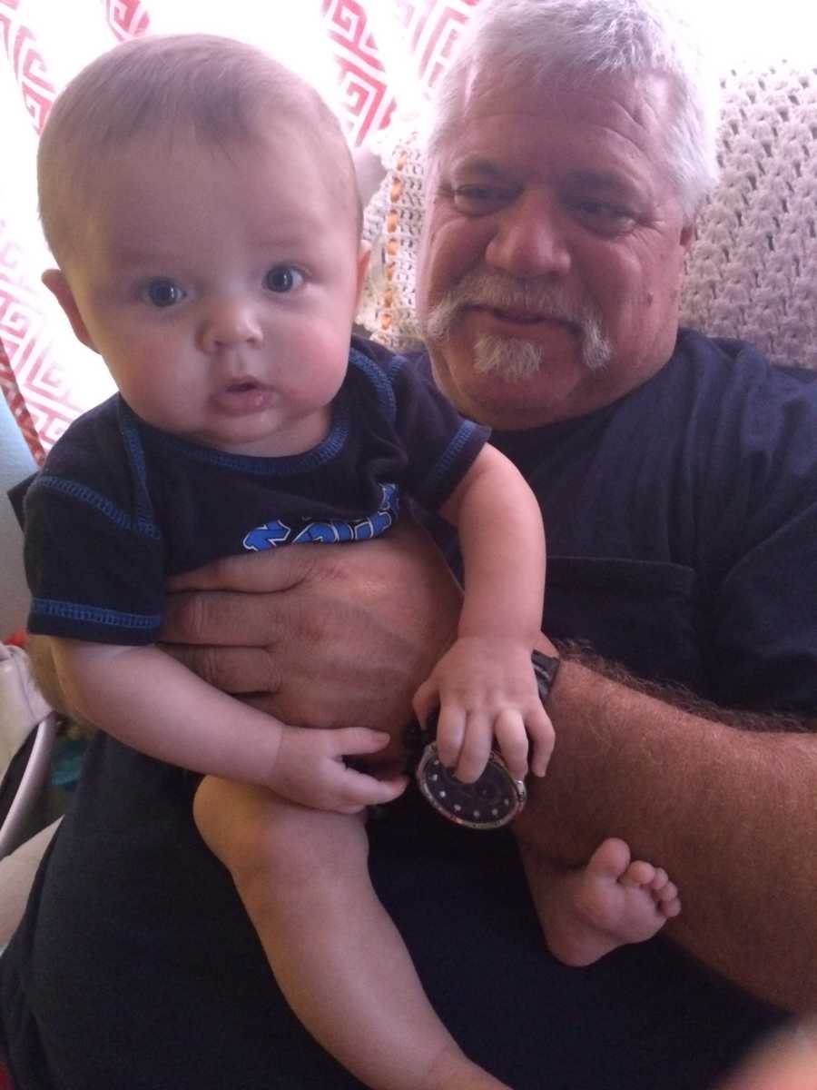 Grandfather sits in chair holding grandson on his lap