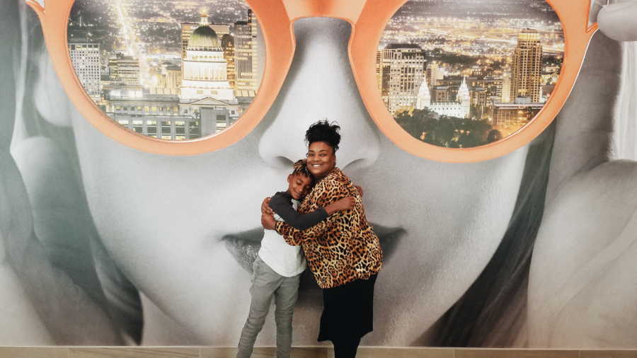 Woman stands with biological son who has now been adopted in front of mural