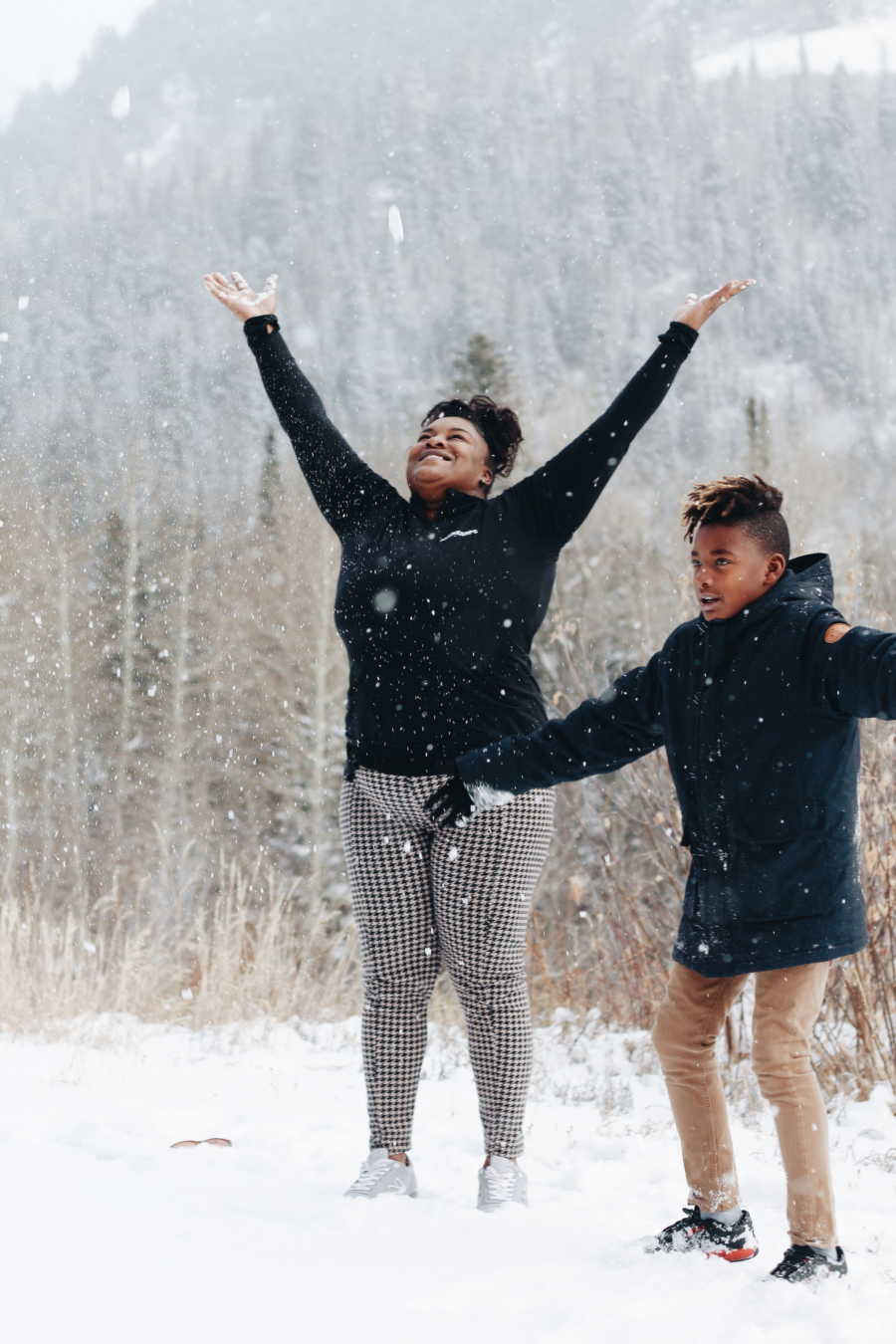 Mother who gave her son up for adoption stands with him outside as she holds her hands in air while snow falls