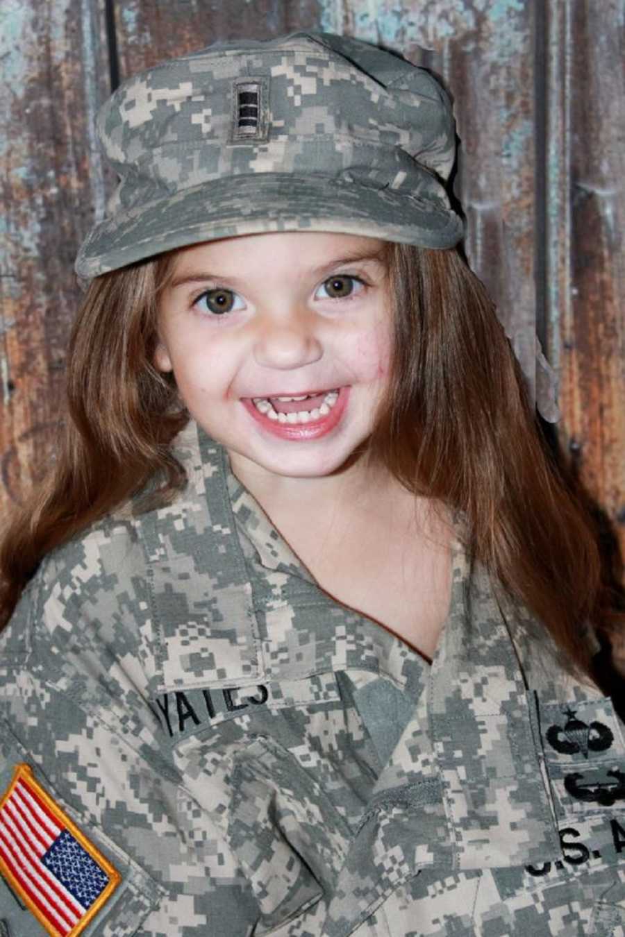 Little girl who has faced a lot of medical issues smiles in army fathers uniform