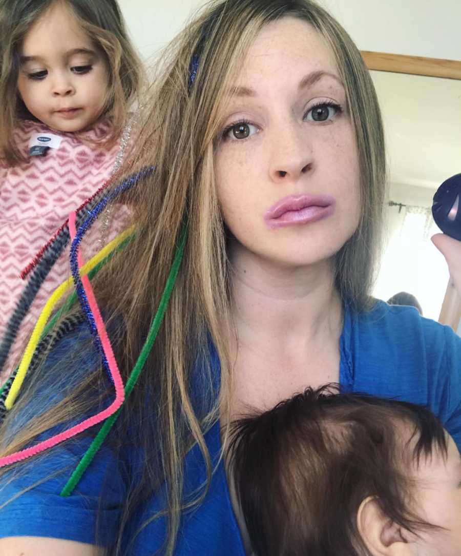 Mother who often feels like a ghost has straight face in selfie with lipstick all over her mouth and child on her lap and behind her
