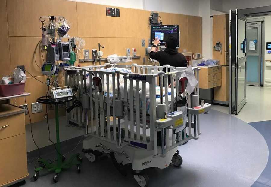 Baby with HLH lays in crib in hospital room