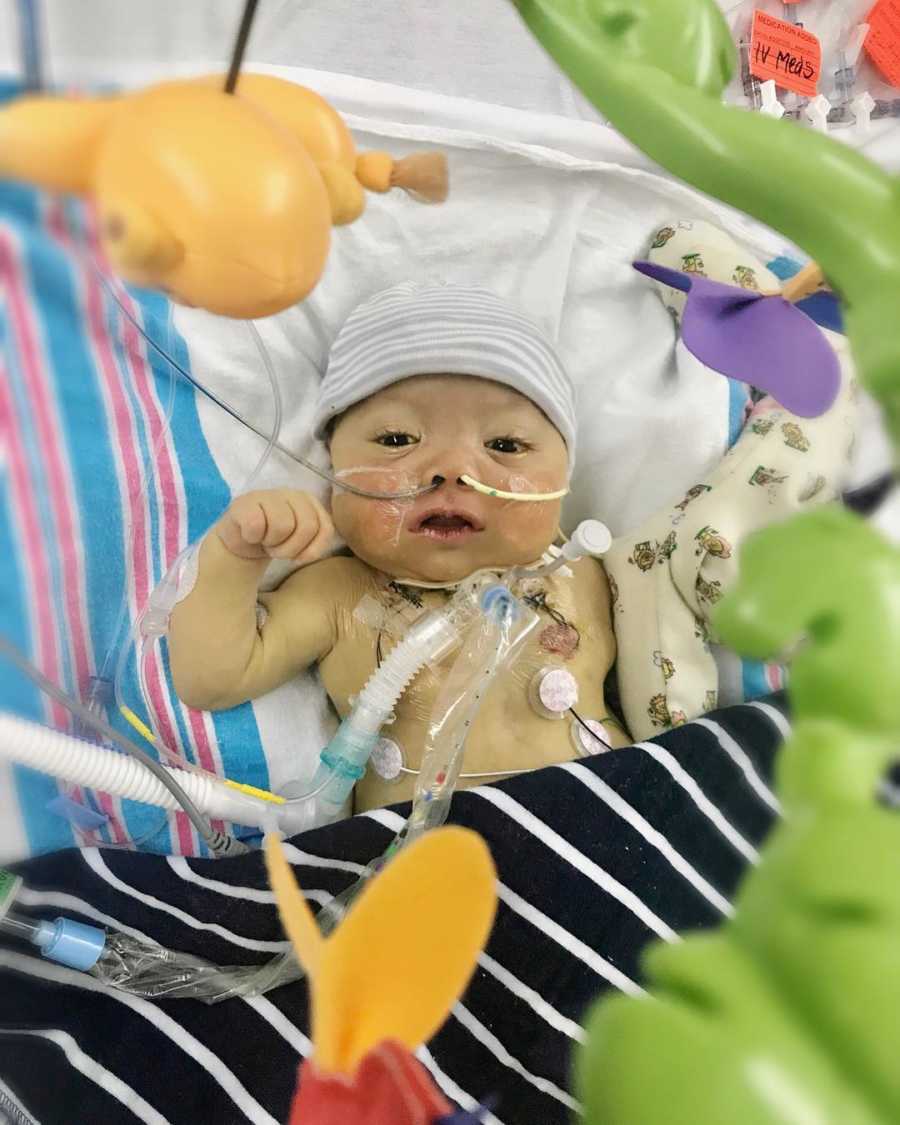 Baby with HLH lying in hospital bed looking up at mobile above him