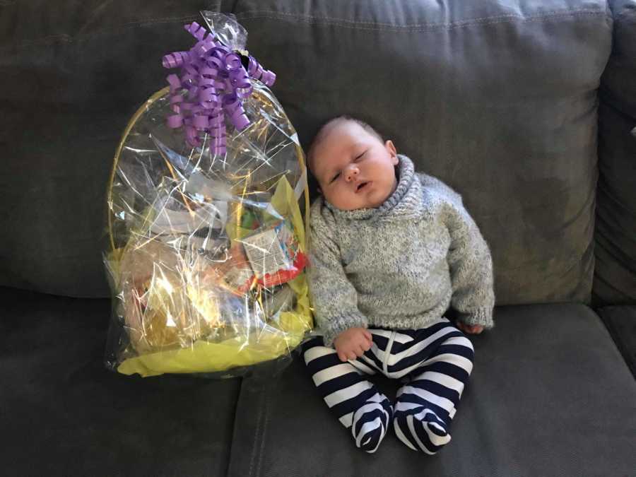 Baby sits on couch beside Easter basket