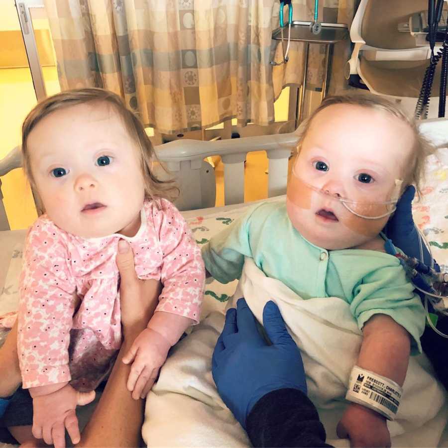 Twin girls sitting up in PICU after one twin has open heart surgery