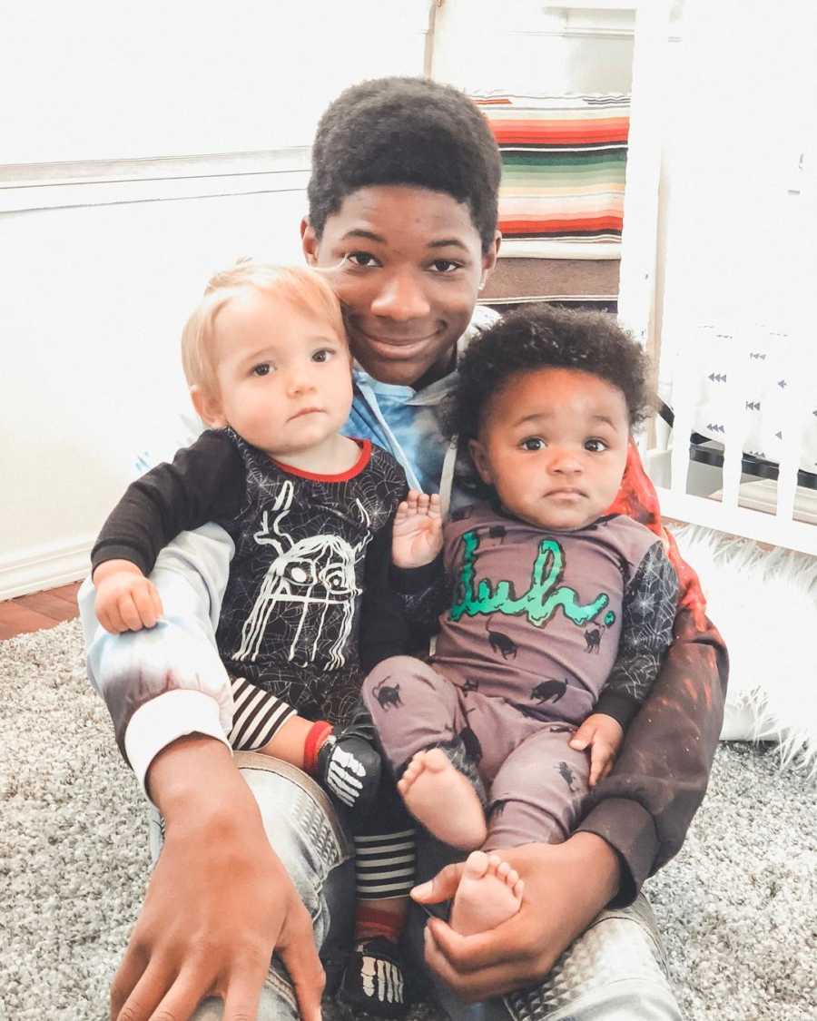 Teen boy sits on ground with his biological brother who was adopted and his brother