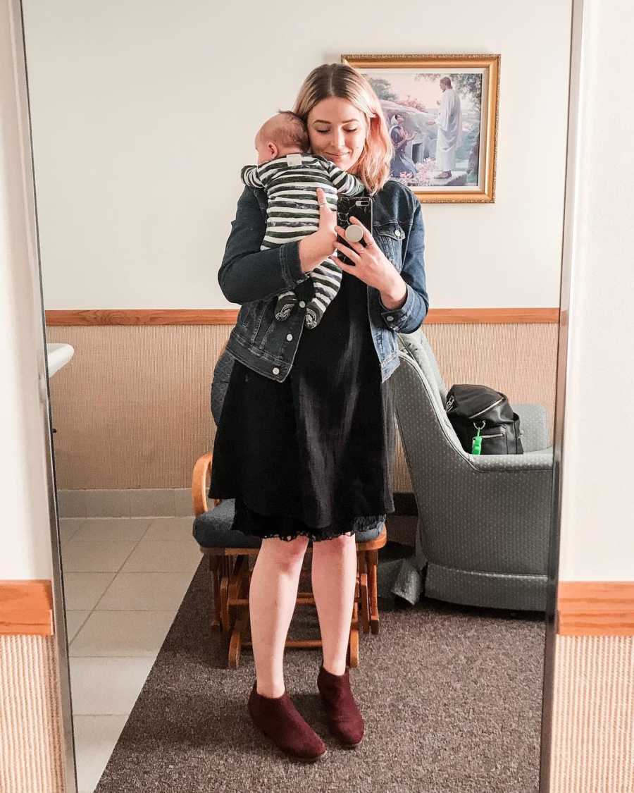 Woman stands holding adopted baby in mirror selfie