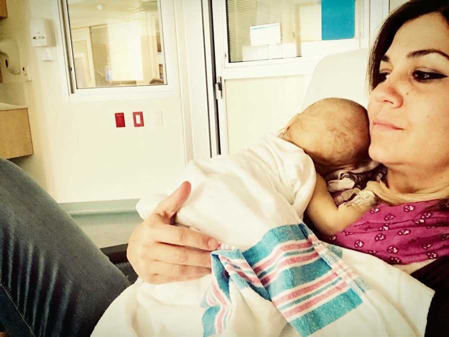 Mother sits in hospital room holding baby with HLH to her chest who she will never bring home