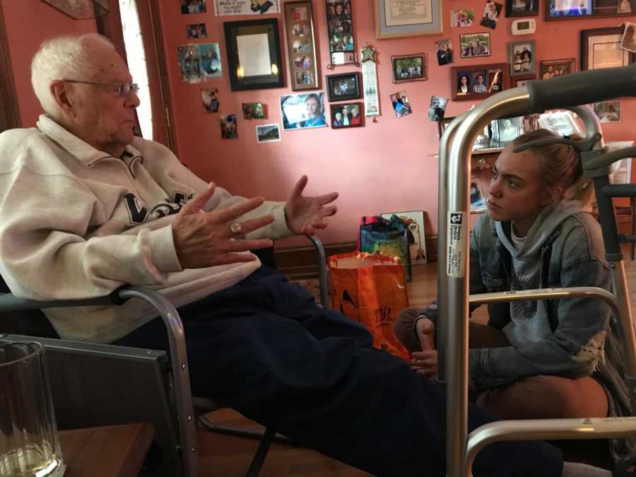 Man sits in chair in home with granddaughter sitting on floor looking up at him